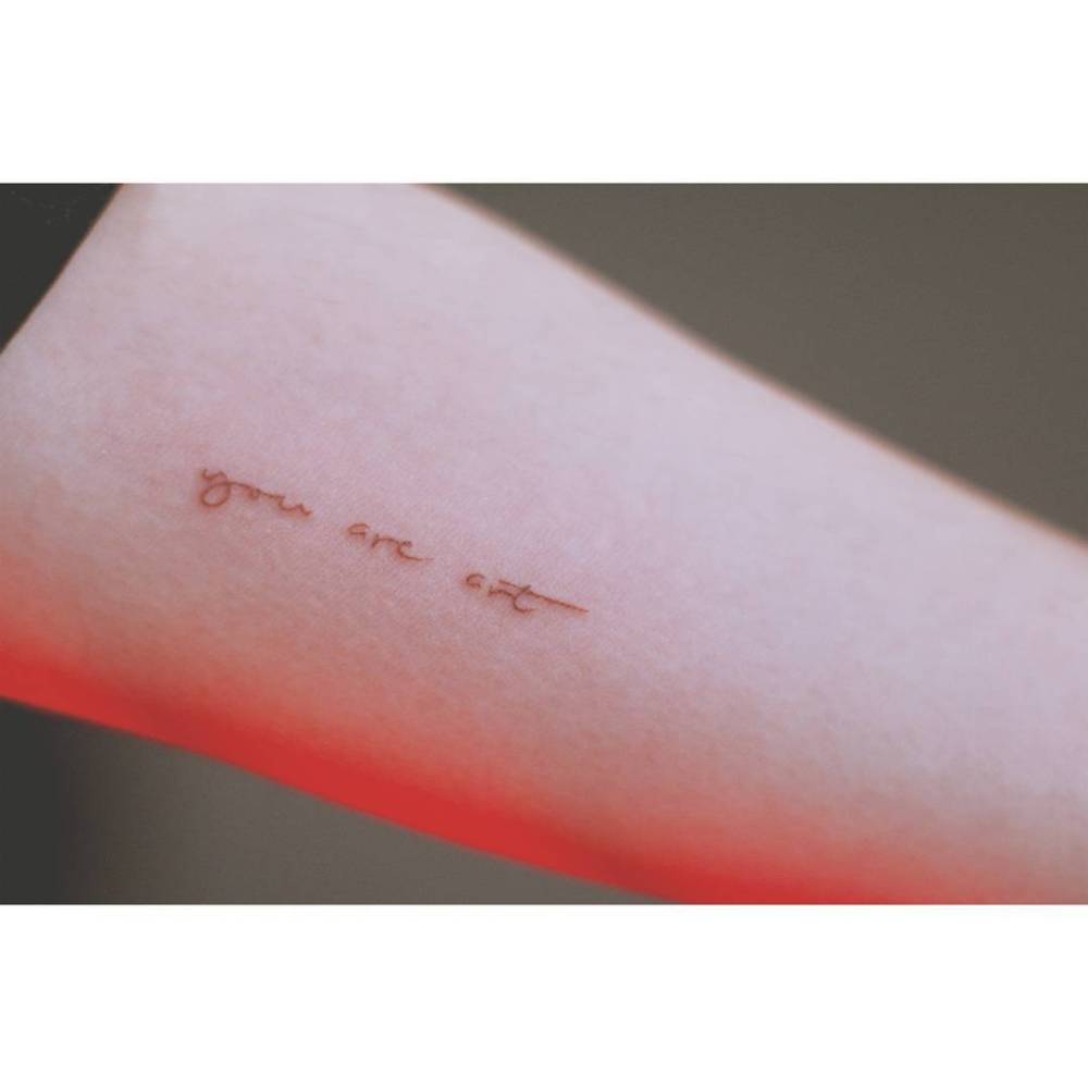 "You are art" lettering tattoo in handwritten font.