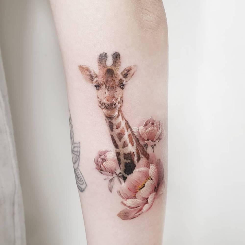 Giraffe portrait tattoo in micro-realistic style located on the inner forearm.