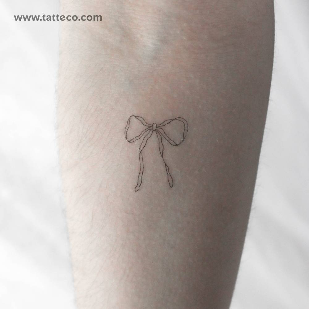 Fine line style ribbon bow temporary tattoo located on the inner forearm.