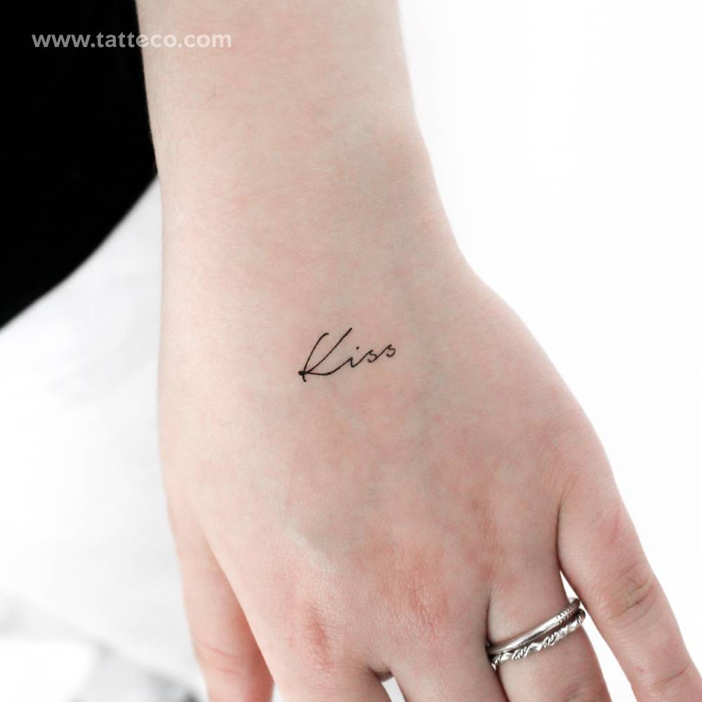 Word "kiss" temporary lettering tattoo located on the hand.