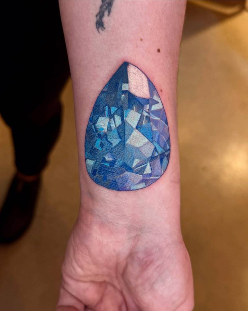 Sapphire tattoo in illustrative style placed on the wrist.