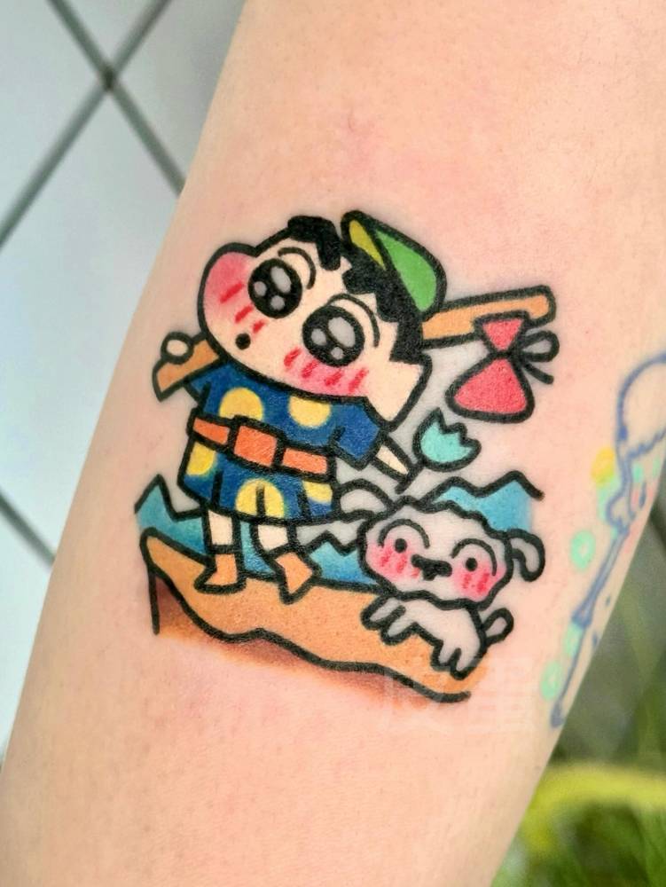 Shin-Chan tattoo in cartoon style done on the upper arm.