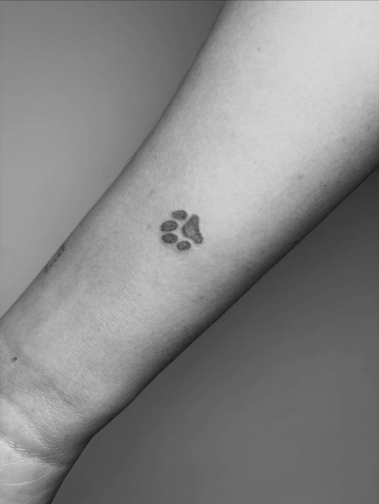 Dotwork style dog paw print tattoo located on the wrist.