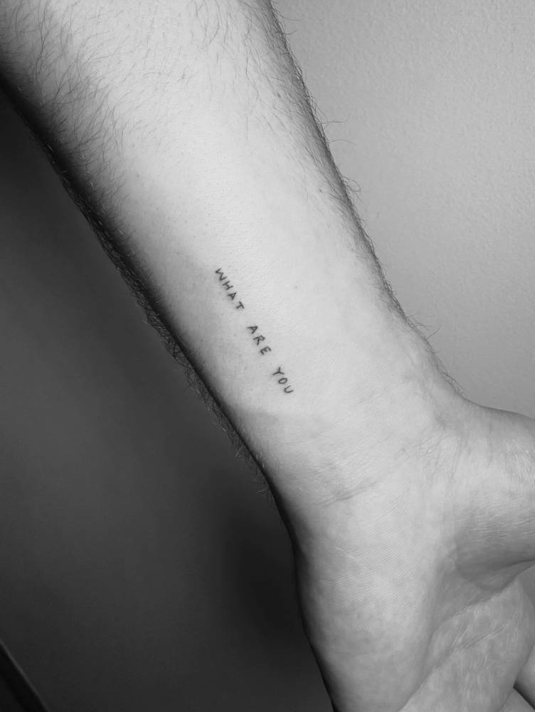 "What are you" lettering tattoo in handwritten font.