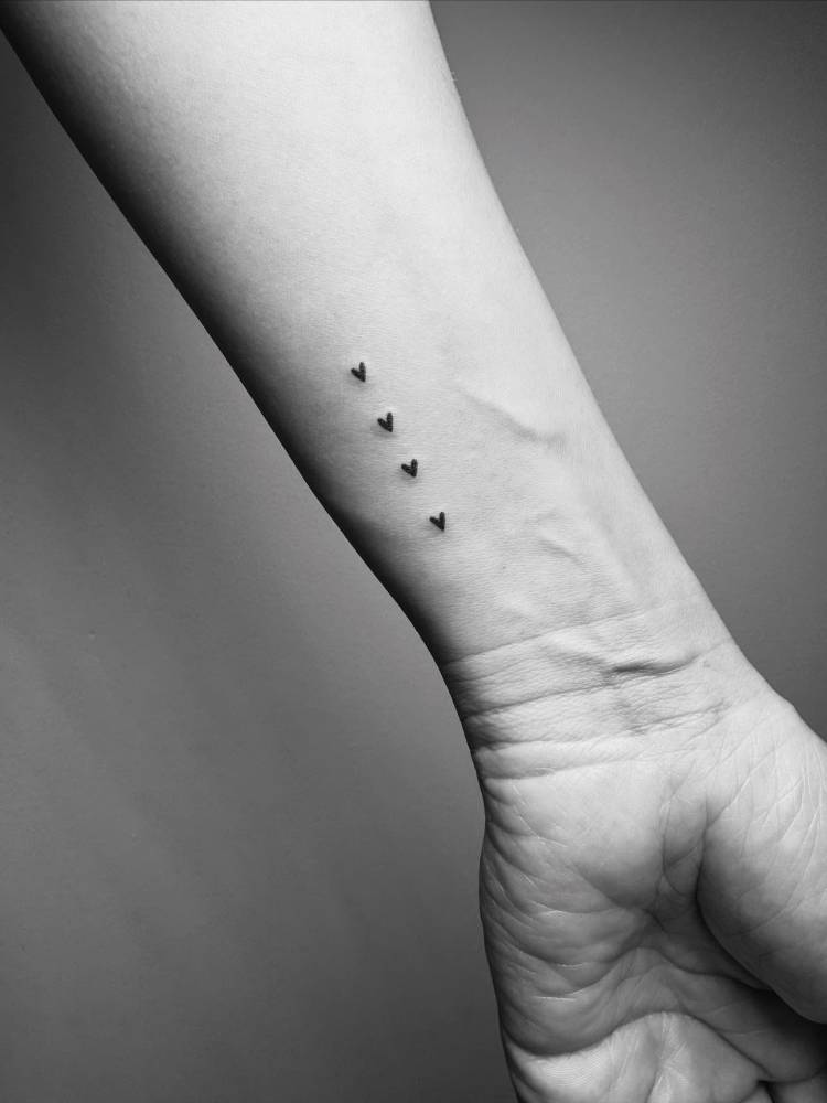 Tiny little hearts in minimalistic style tattooed on the wrist.