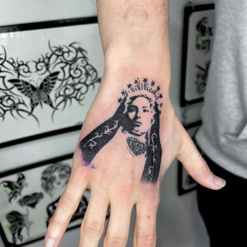 Virgin Mary tattoo in stencil style located on the hand.