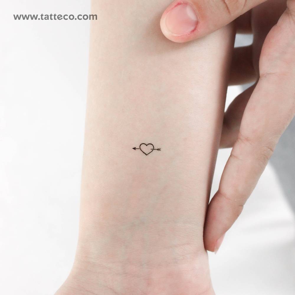 Little minimalistic heart and arrow temporary tattoo located on the wrist.