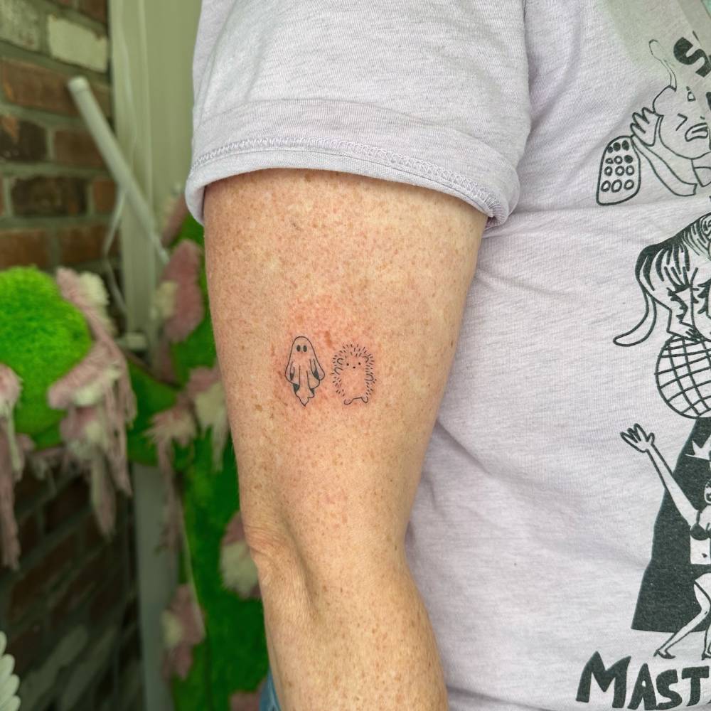 Hand poked ghost and hedgehog tattoo located on the upper arm.