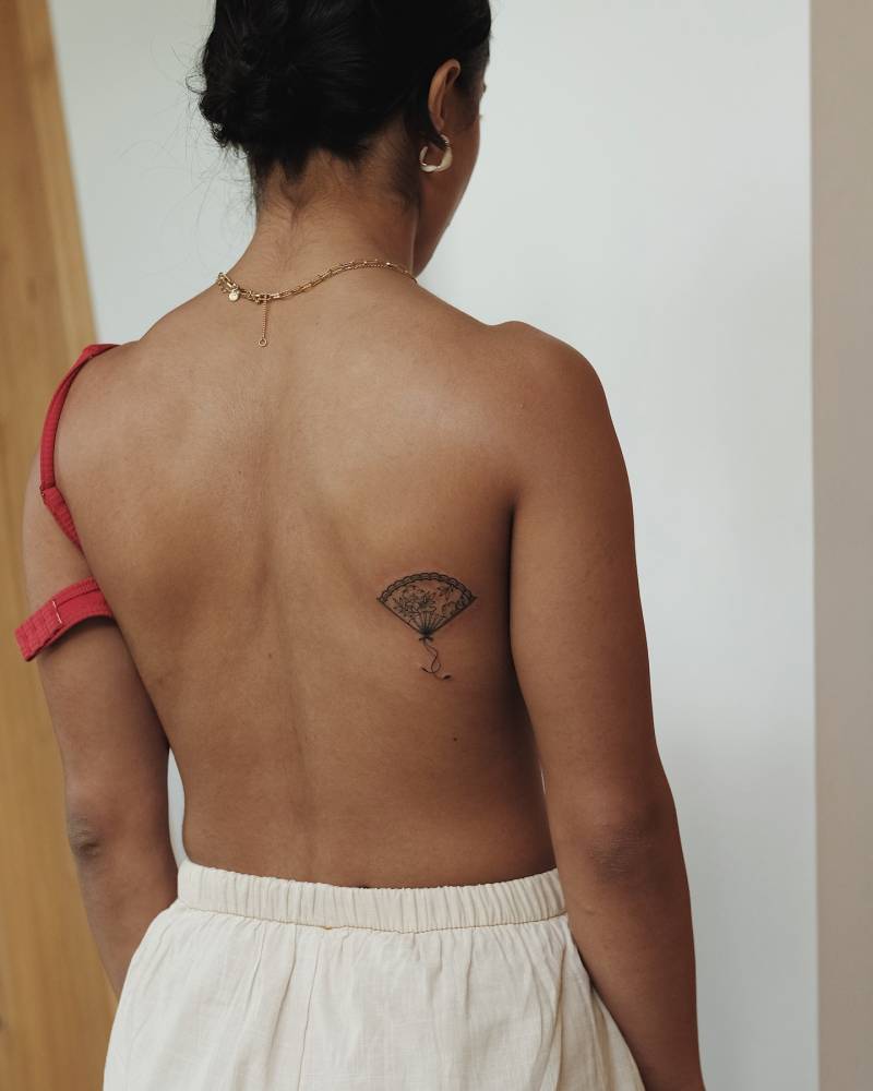 Illustrative style hand fan tattoo located on the shoulder blade.