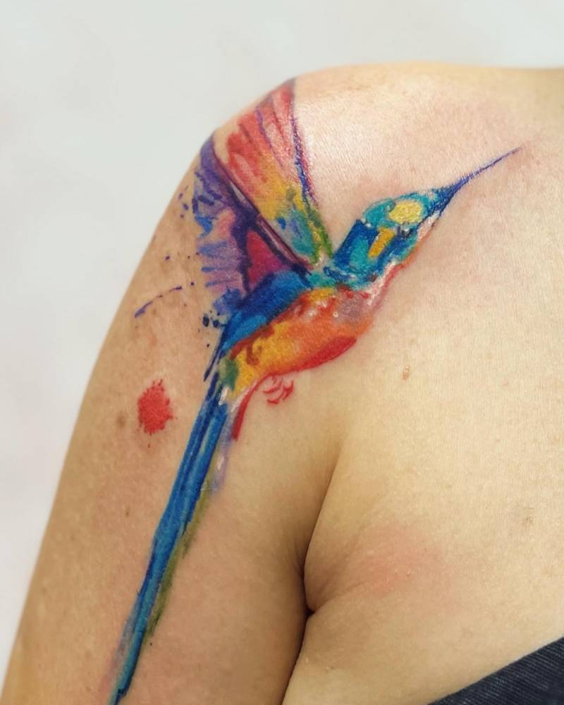 Hummingbird tattoo in watercolor style located on the shoulder.