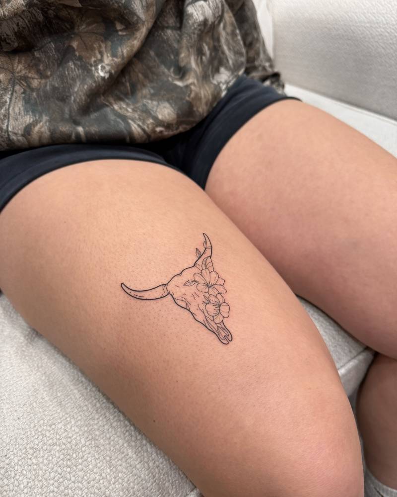 Bull skull tattoo located on the thigh, done in fine line style.