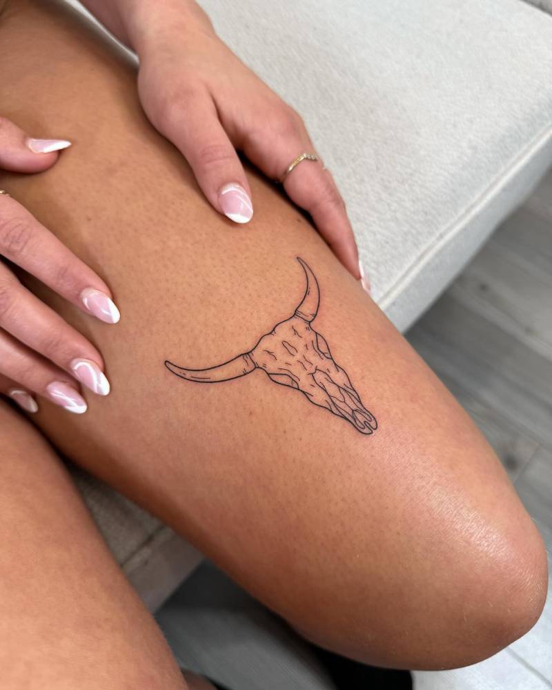 Bull skull tattoo located on the thigh, fine line style.