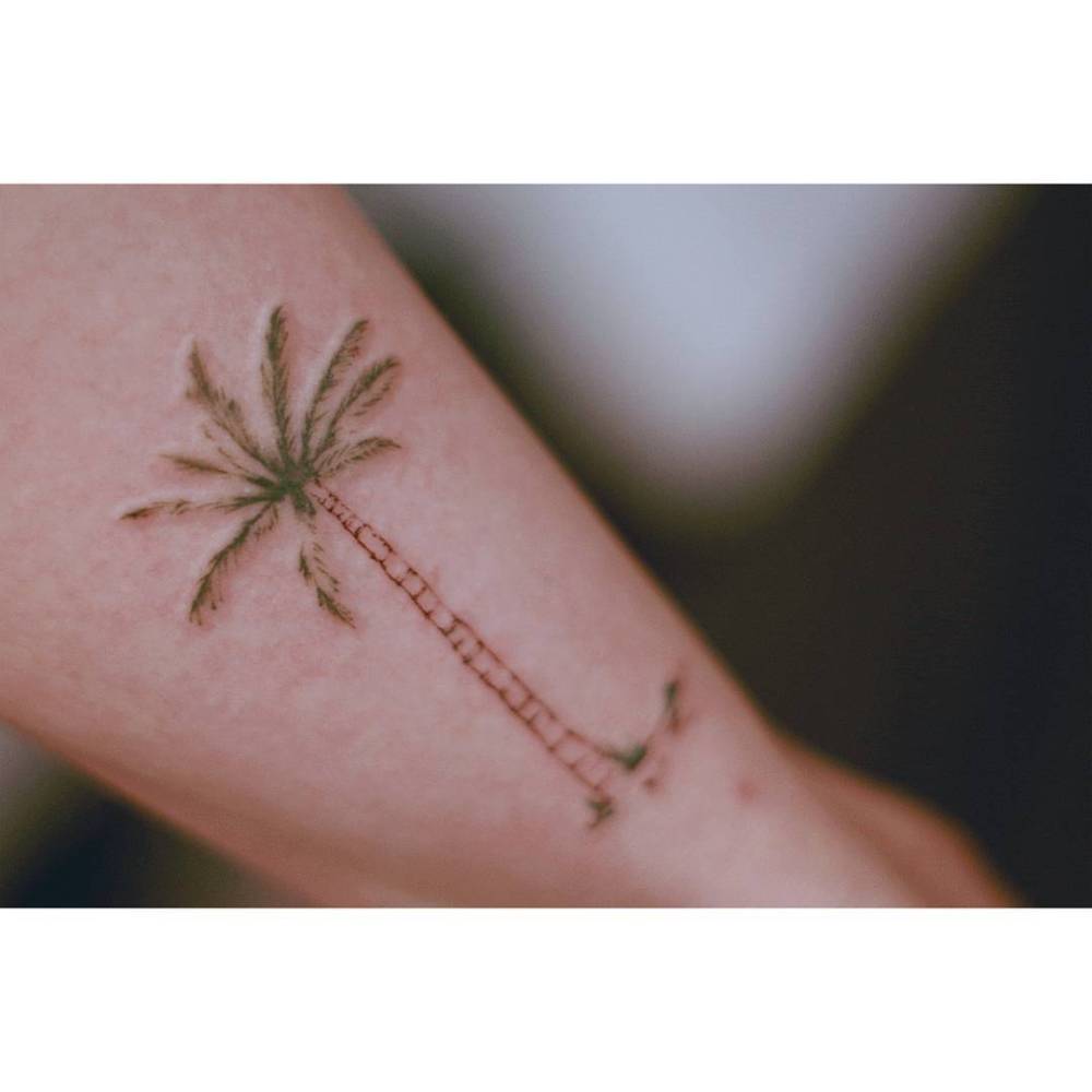 Watercolor style palm tree tattoo located on the achilles.
