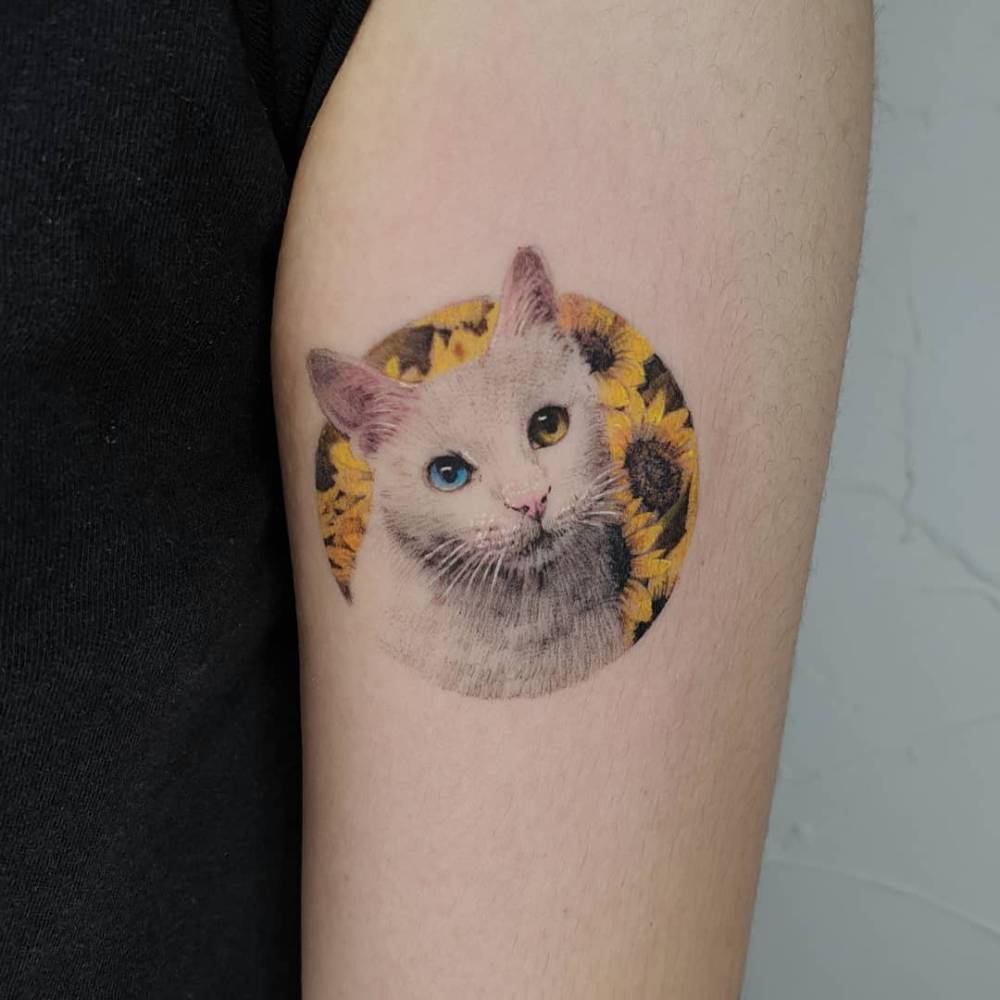 Cat portrait tattoo done in micro-realism, located on the upper arm.