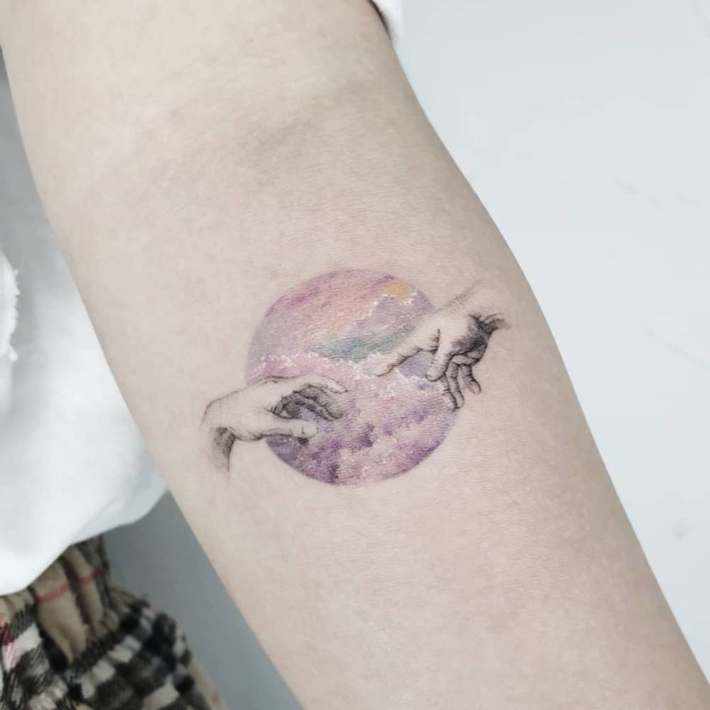Watercolor style 'The Creation of Adam' hands tattoo located on the inner forearm.