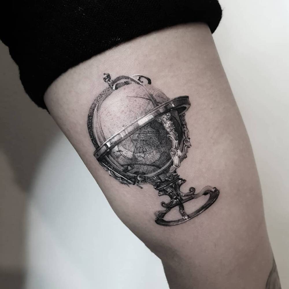 World globe tattoo placed on the inner arm, micro-realistic style.