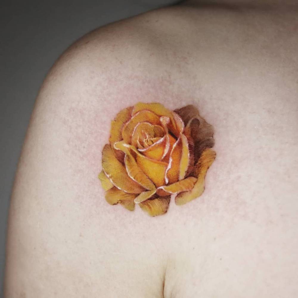 Yellow rose tattoo in realism located on the shoulder.