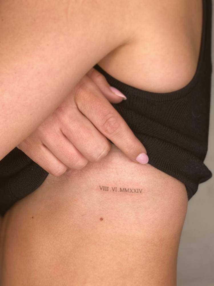 Date in roman numerals tattoo located on the rib.