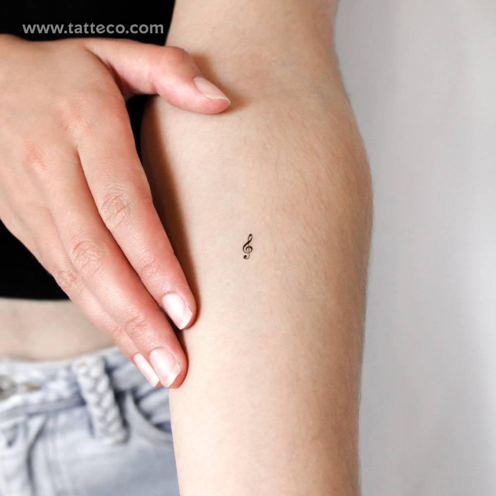 Tiny minimalistic treble clef temporary tattoo located on the inner forearm.