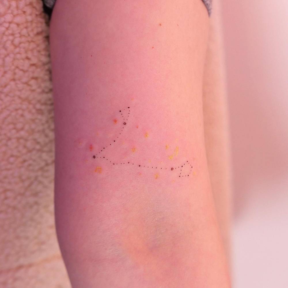 Minimalistic style Pisces constellation tattoo located on the bicep.