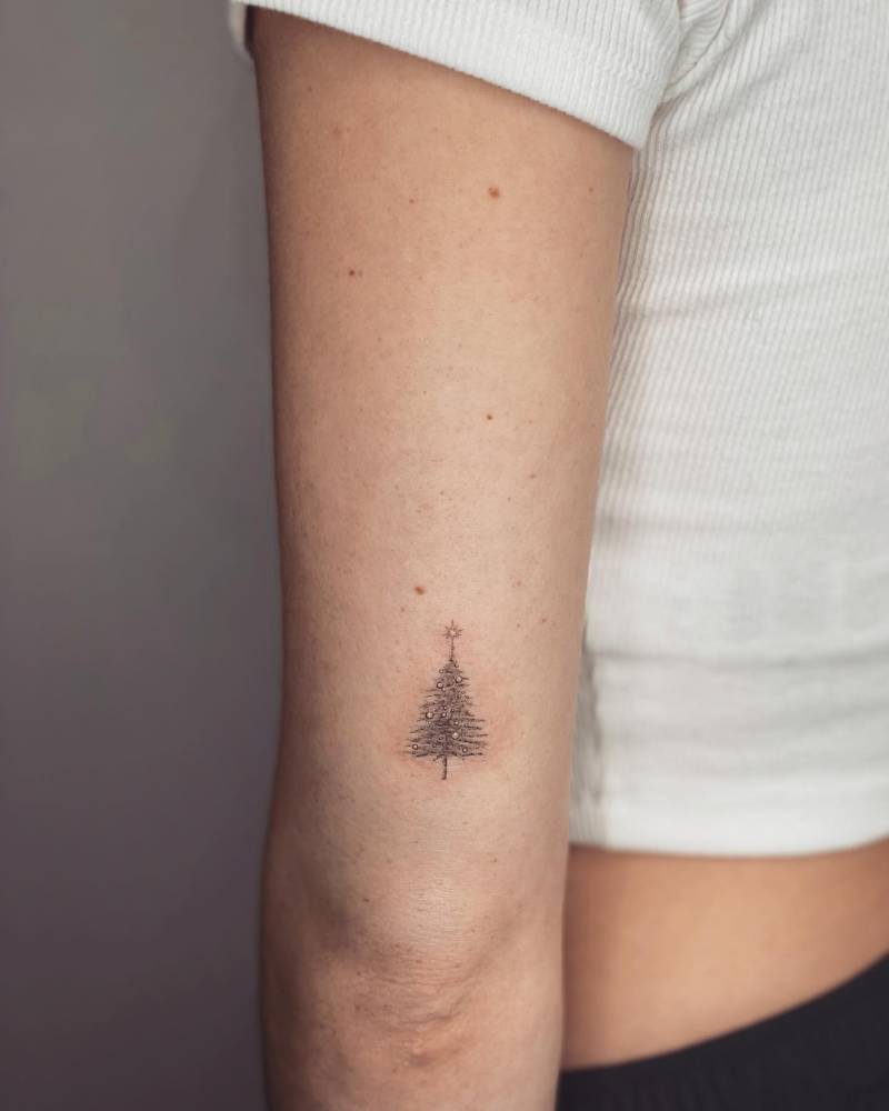 Micro-realistic style Christmas tree tattoo located on the tricep.