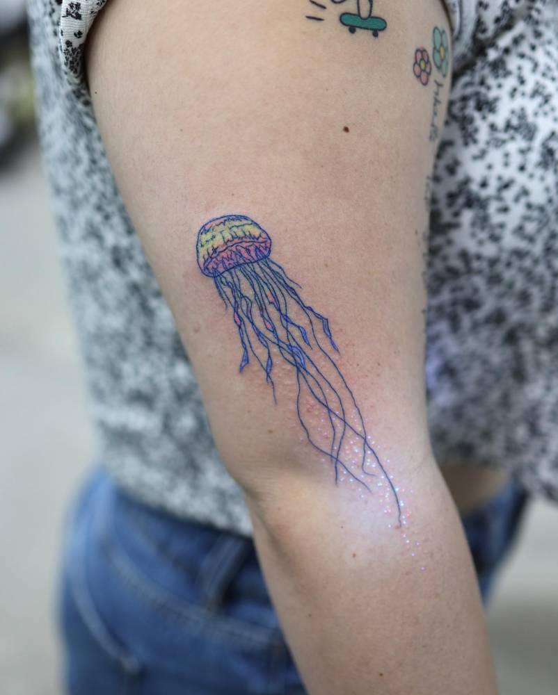 Jellyfish tattoo located on the upper arm, illustrative style.