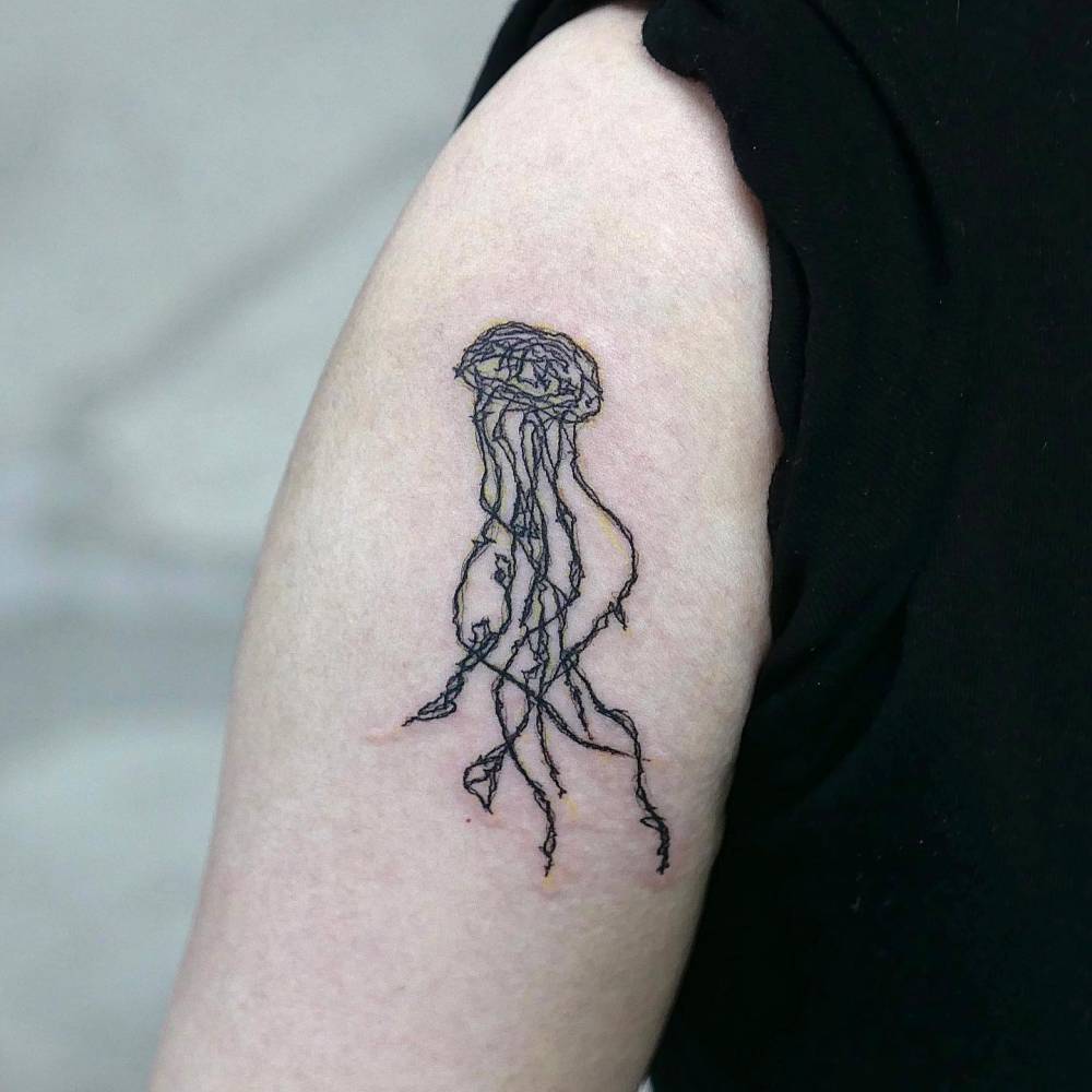 Illustrative style jellyfish tattooed on the upper arm.