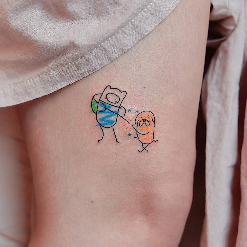 Finn and Jake tattooed on the thigh, cartoon style.