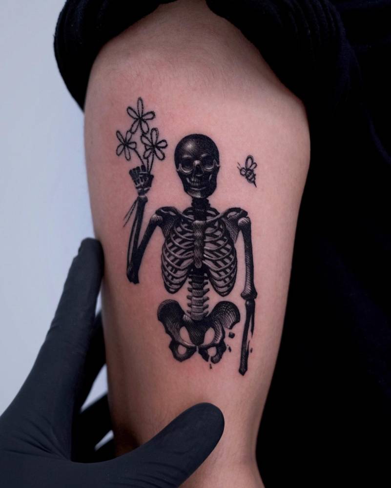 Blackwork style skeleton tattoo placed on the upper arm.