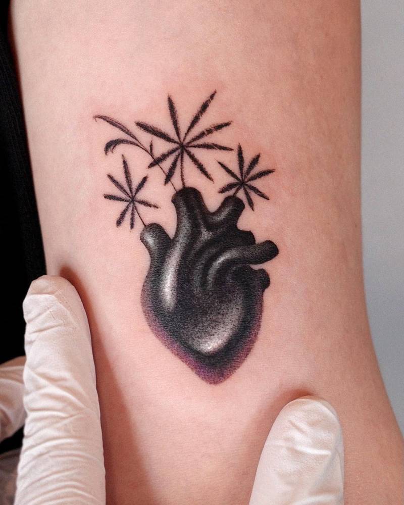 Anatomical heart with flowers tattoo located on the bicep.