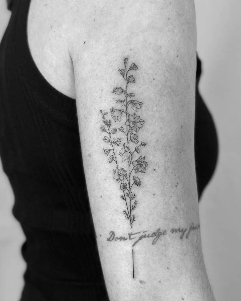 Delphinium tattoo on the upper arm, done in fine line.