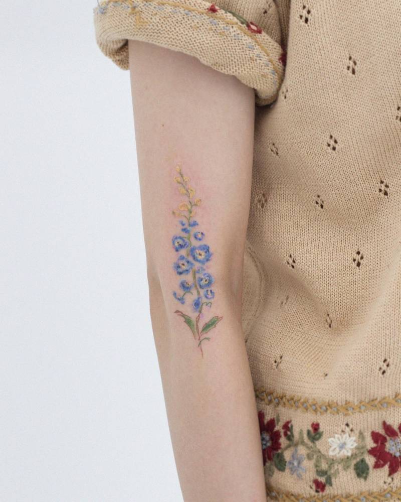Delphinium tattoo placed on the upper arm, watercolor style.