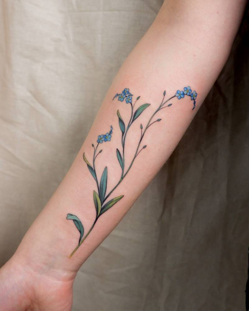 Forget-me-not flowers tattooed on the inner forearm.