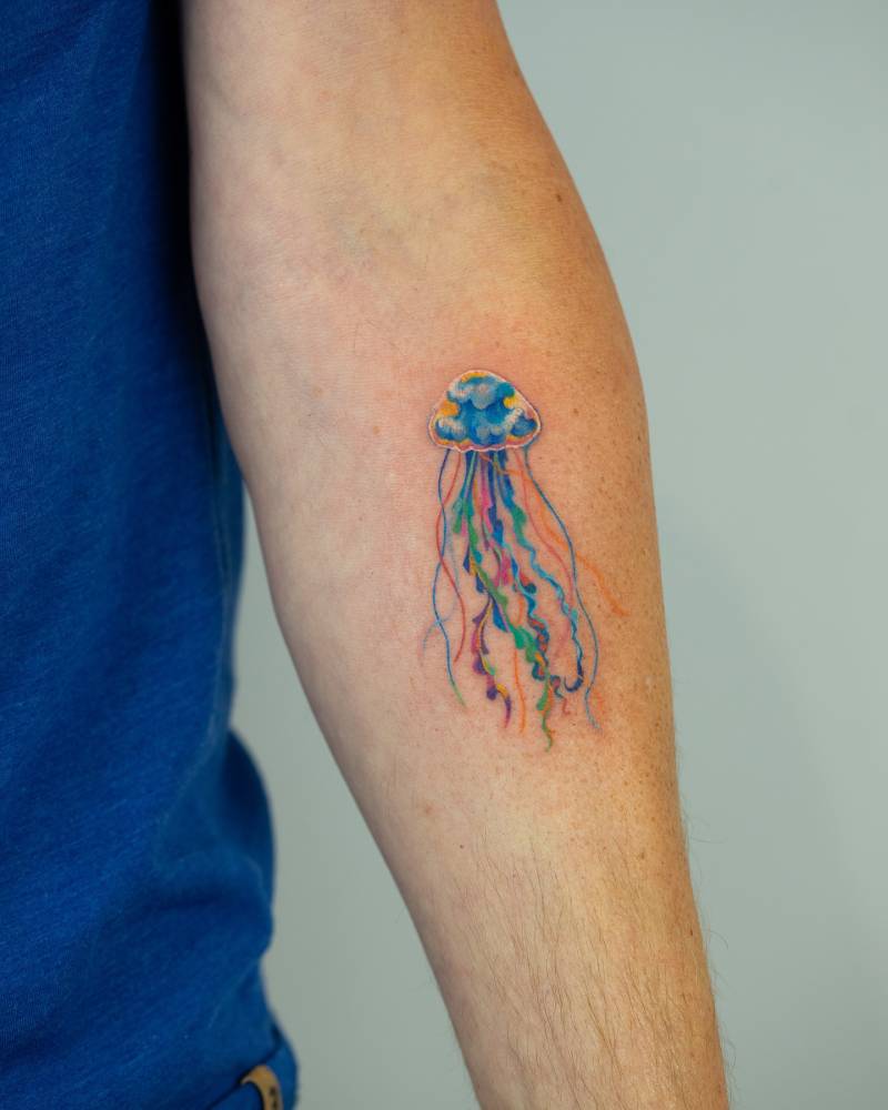 Watercolor style jellyfish tattoo located on the inner forearm.