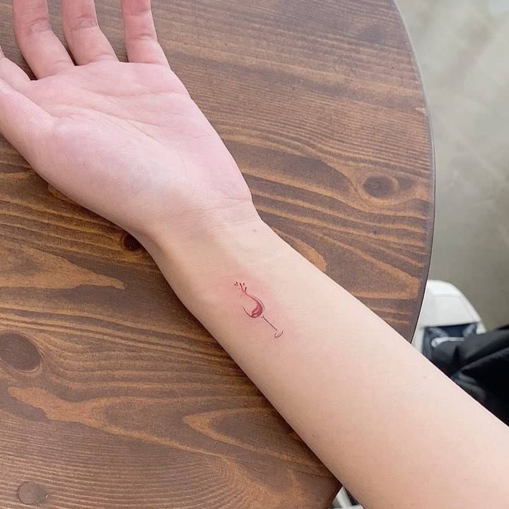 Minimalistic style wine glass tattoo located on the wrist.