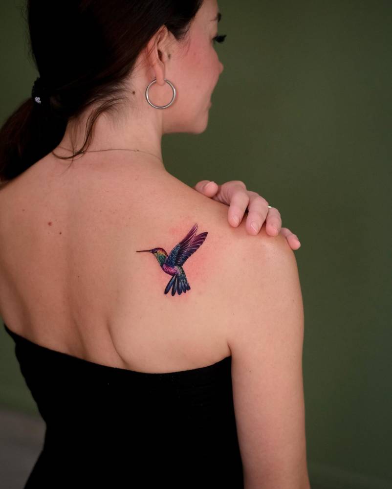 Illustrative style hummingbird tattoo located on the shoulder blade.