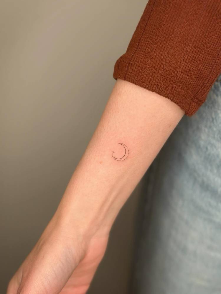 Little crescent moon in fine line style located on the wrist.