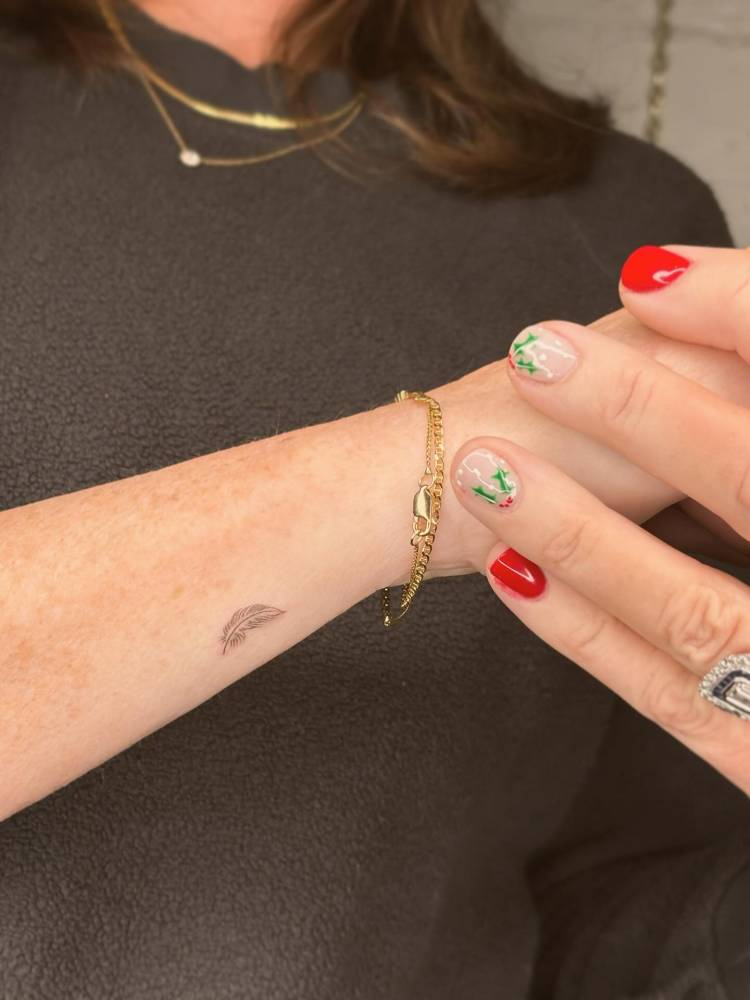 Tiny minimalistic feather tattoo placed on the wrist.