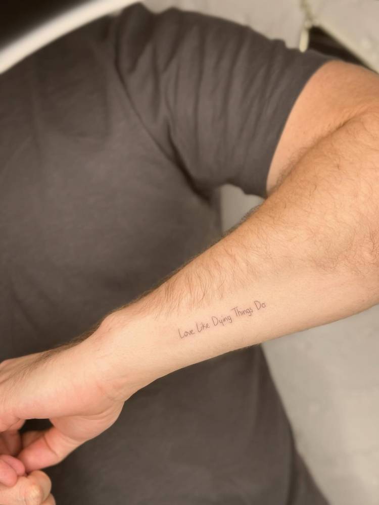 "Love like dying things do" lettering tattoo handwritten on the wrist.