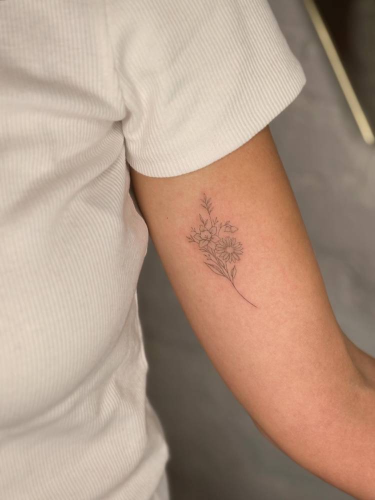 Fine line style flower bouquet tattoo done on the inner arm.