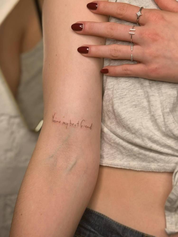 "You're my best friend" lettering tattoo located on the bicep.