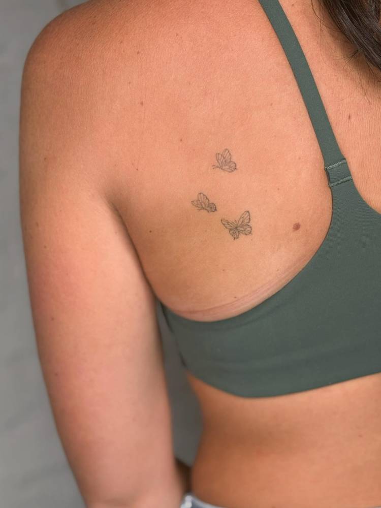 Fine line style three butterflies tattoo located on the shoulder blade.