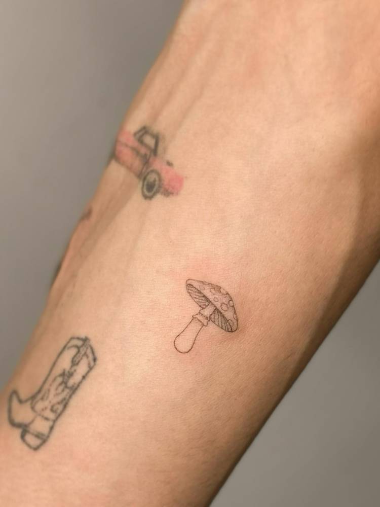 Illustrative style mushroom tattoo located on the inner forearm.