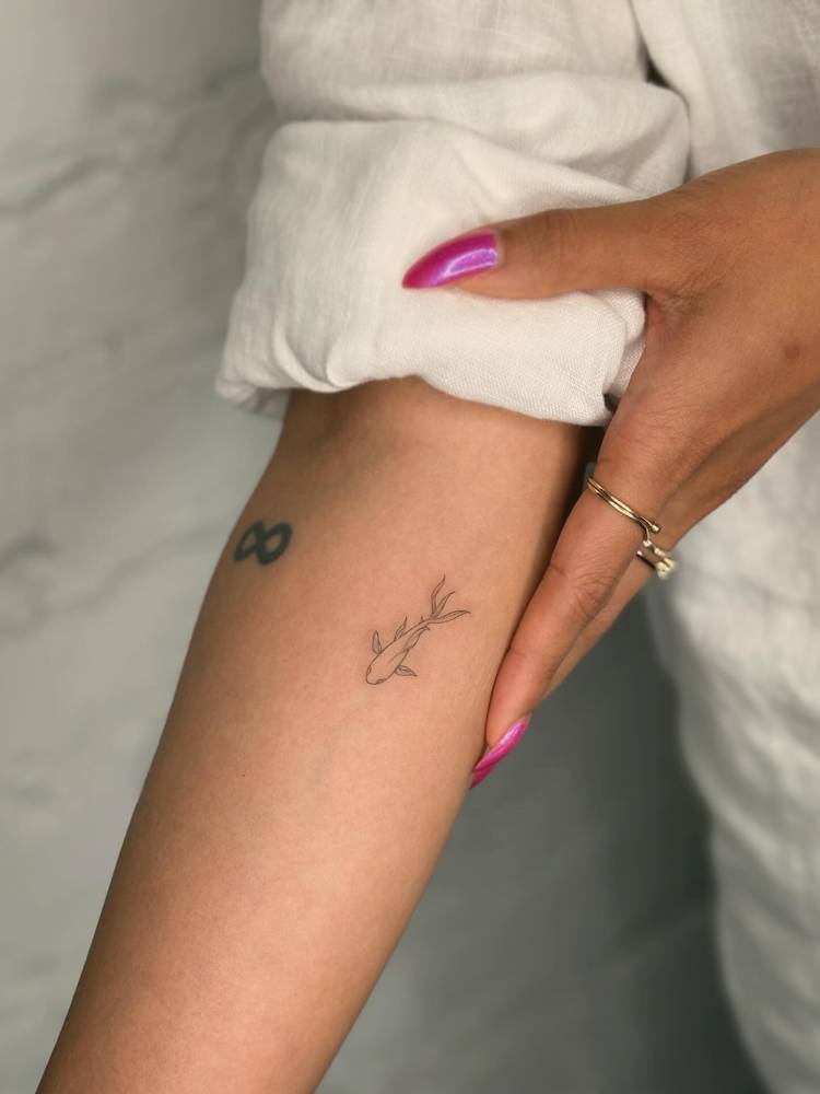 Koi fish in fine line style tattooed on the inner forearm.
