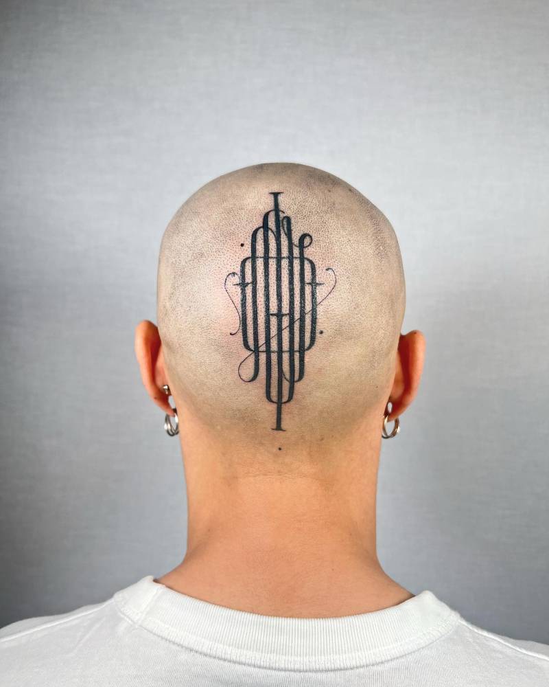 Monogram lettering tattoo located on the head.