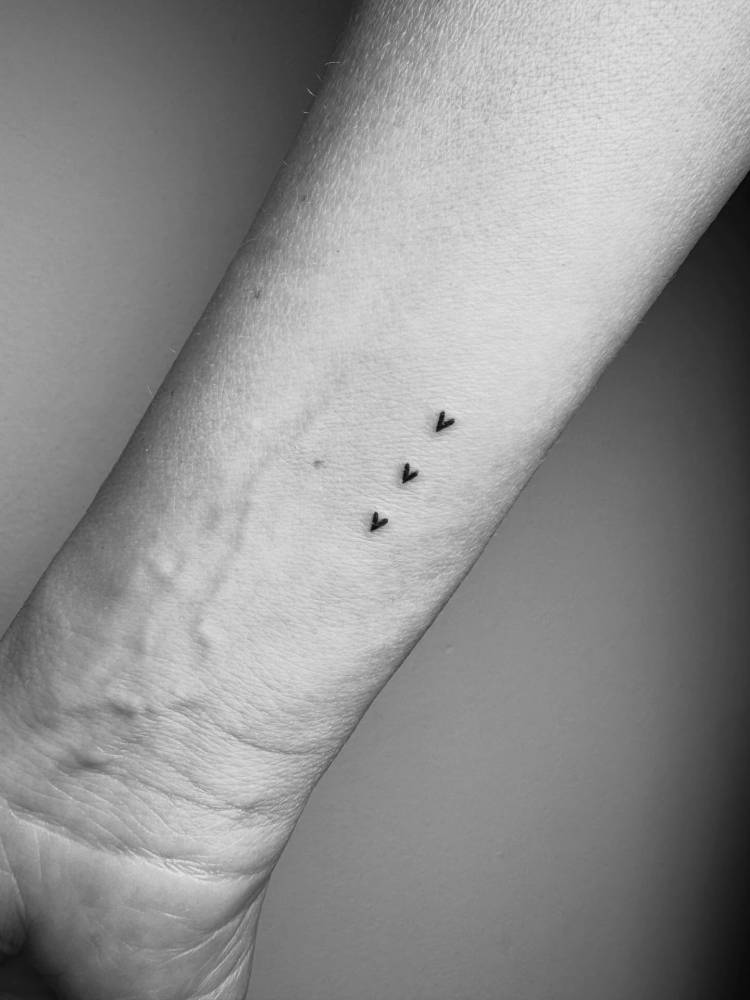 Three little hearts in minimalistic style tattooed on the wrist.