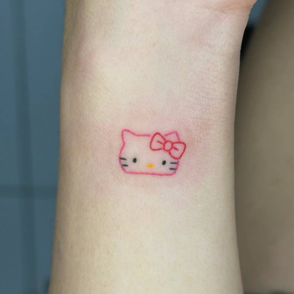 Hand poked Hello Kitty portrait tattoo located on the wrist.