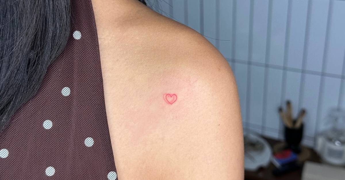 Tiny minimalistic red heart tattoo placed on the