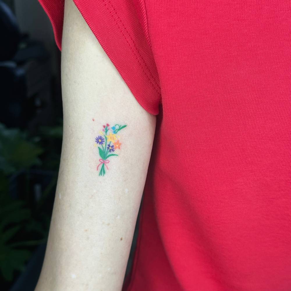 Hand poked flower bouquet tattoo done on the tricep.