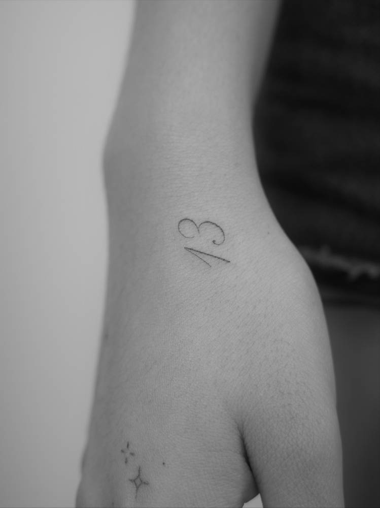 Lucky number "13" tattoo located on the wrist.